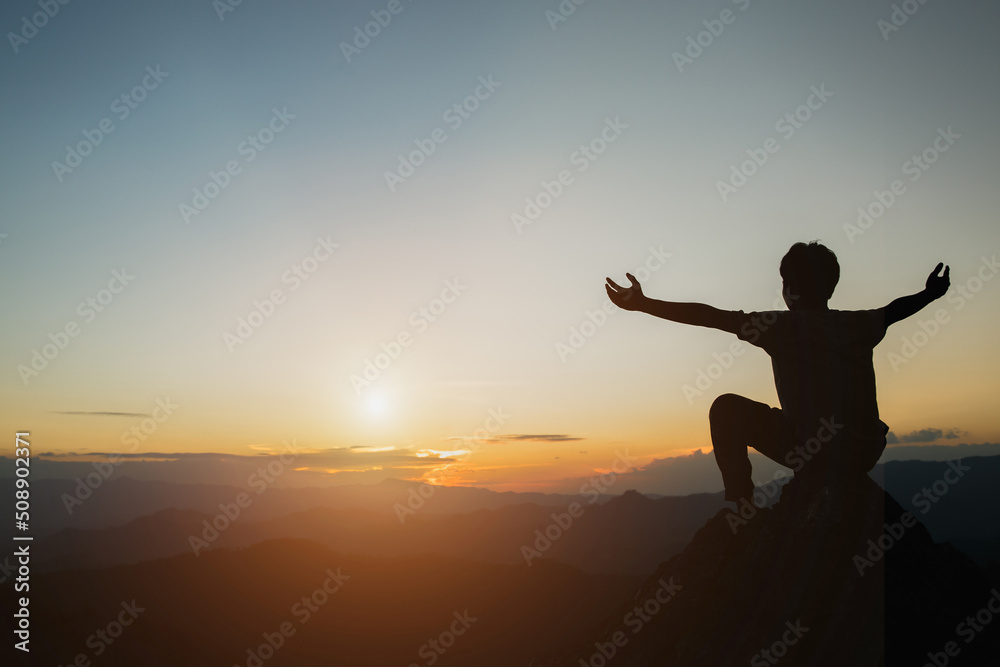 Silhouette of teenage boy praying to God on  autumn sunrise background, religious concept.