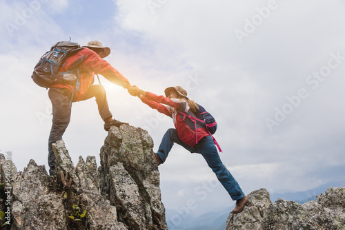 Young couple traveling, Helping hand, hiker woman getting help on hike smiling happy overcoming obstacle, Tourist backpackers walking in forest.