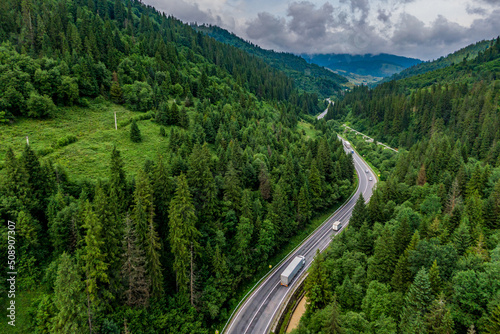 cargo truck on the higthway. cargo delivery driving on asphalt road through the mountains. seen from the air. Aerial view landscape. drone photography.
