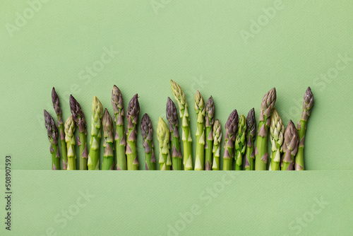 Young asparagus sticks on green background from above. Diet food concept. photo