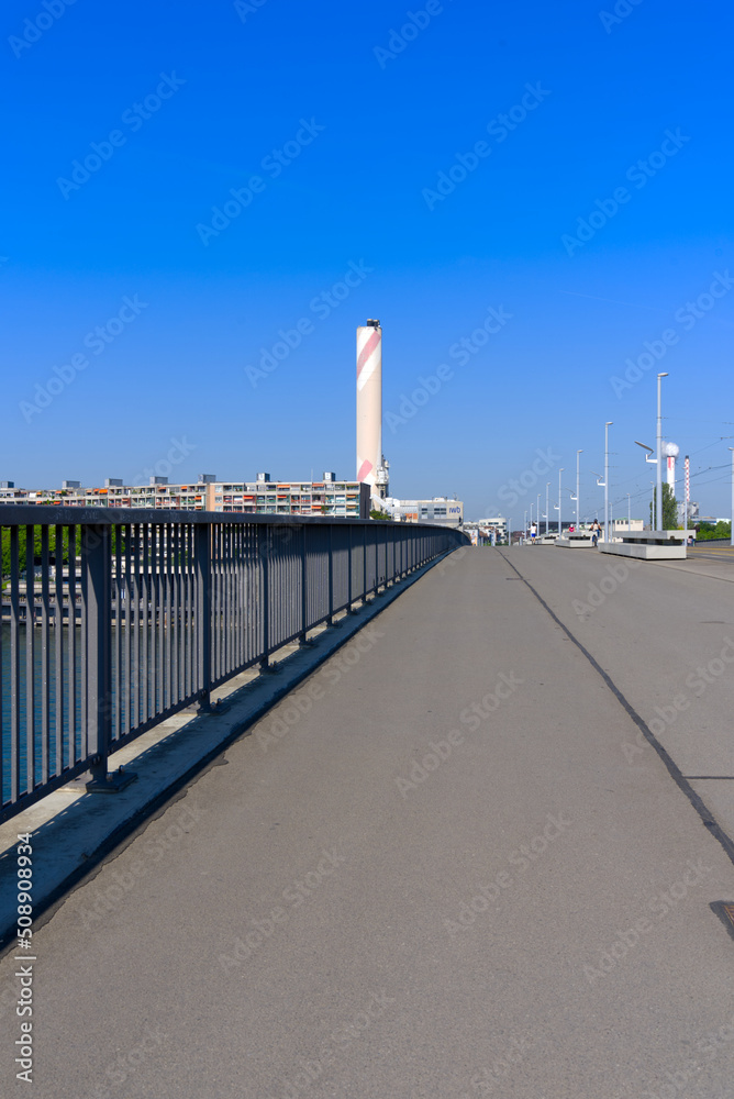 Bridge named Dreirosenbrücke with tramway and chimney of incineration plant in the background at City of Basel on a sunny spring day. Photo taken May 11th, 2022, Basel, Switzerland.