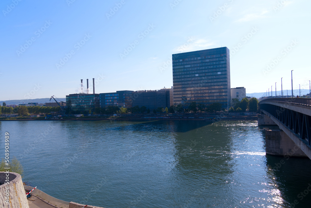 Facades of factory buildings with tree chimneys in backlight at industrial district of City of Basel with Rhine River on a sunny spring day. Photo taken May 11th, 2022, Basel, Switzerland.