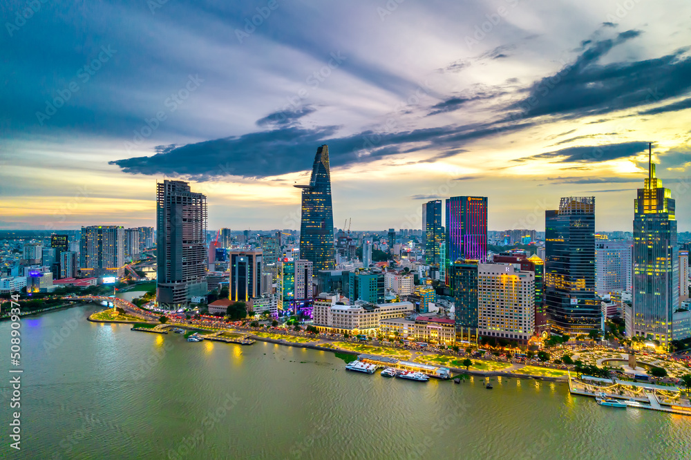 Fototapeta premium Aerial view of beautiful skyscrapers along the river at sunset sky light flowing down urban development in Ho Chi Minh City, Vietnam.