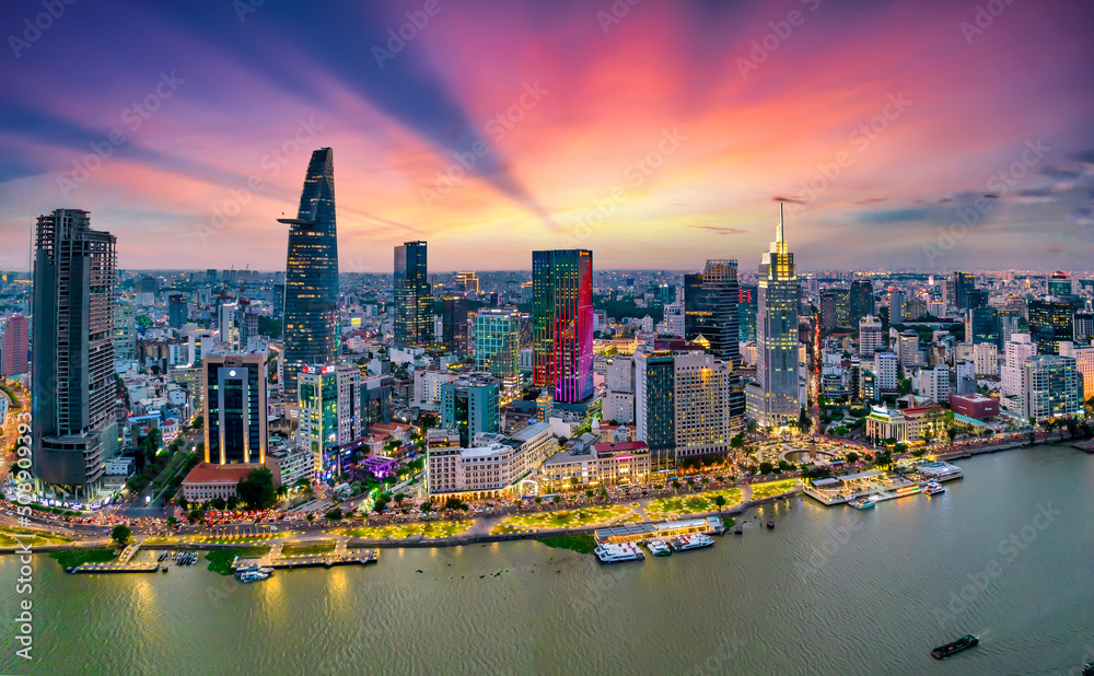 Fototapeta premium Aerial view of beautiful skyscrapers along the river at sunset sky light flowing down urban development in Ho Chi Minh City, Vietnam.