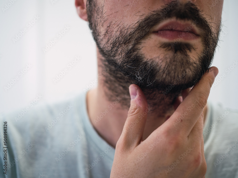 Obraz premium Unrecognizable caucasian man touching his beard with fingers. Man care concept