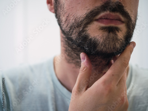 Unrecognizable caucasian man touching his beard with fingers. Man care concept
