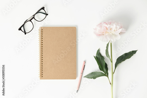 Fotografie Minimal styled flat lay with peony flower and blank notebook