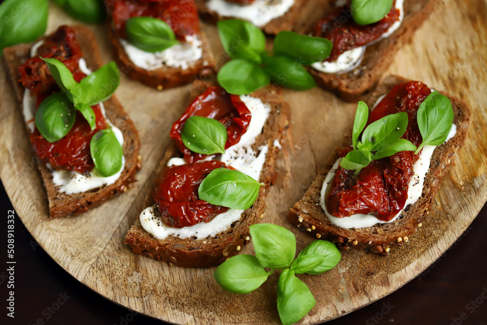 Bruschetta with dried tomatoes and basil. Open sandwiches on rye bread with tomatoes.
