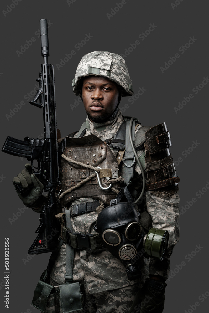 Portrait of african military man dressed in modern camouflage uniform holding rifle.