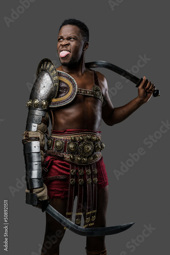 Photography of cheerful ancient gladiator of african ethnic showing his tongue.