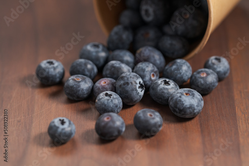Wallpaper Mural Ripe blueberries spilling from paper cup on wood table Torontodigital.ca