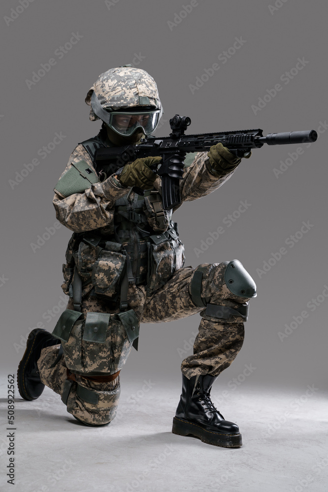 Studio shot of militant woman dressed in protective suit aiming rifle looking away. Studio shot of militant woman dressed in protective suit aiming rifle looking away.