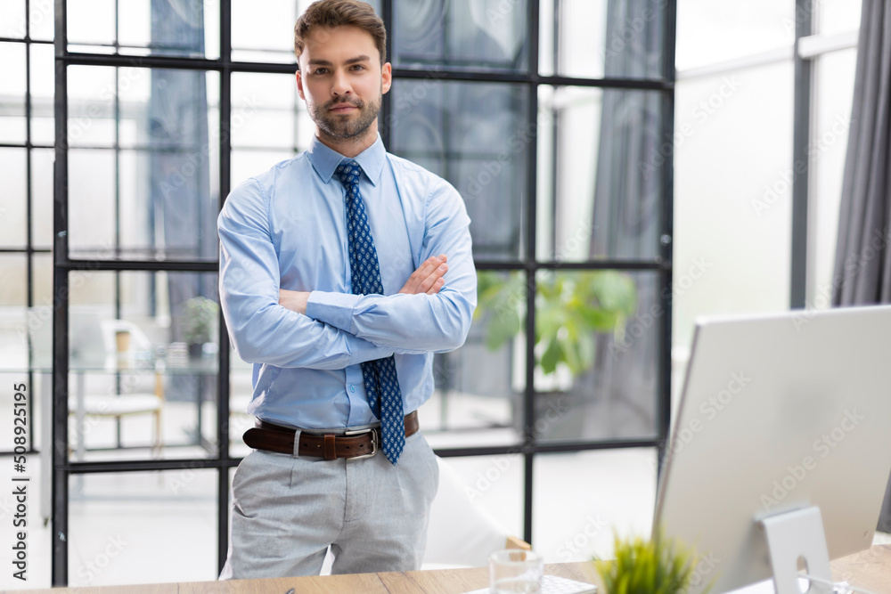 Handsome young businessman standing in modern office.