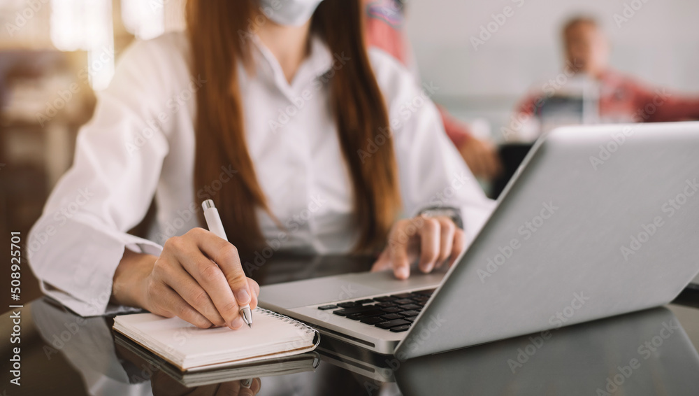 Hands businesswoman taking notes in a notebook and using a laptop in the office. Hands businesswoman taking notes in a notebook and using a laptop in the office.