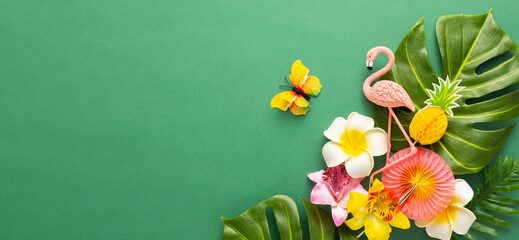 Exotic tropical summer background. Summer beach party concept. Pink flamingo, tropical leaves, orchid flowers and other accessories on green background. Flat lay, copy space.