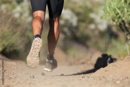 Athlete running sport feet on trail, selective focus on sole.Training workout on off road trail track design in advertising poster style