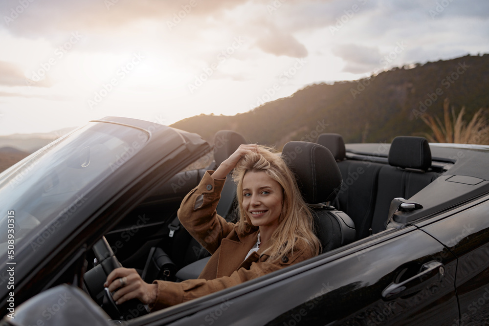 Close up portrait of cheerful young beautiful woman smiling to camera while driving a cabriolet car