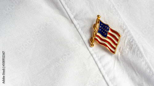 Metal badge with the US flag on a white fabric of a women's shirt
