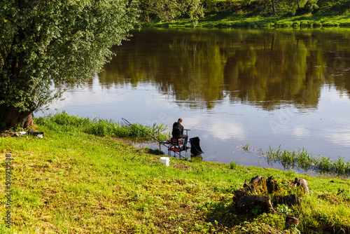 Fisherman sitting by the river on sunny day