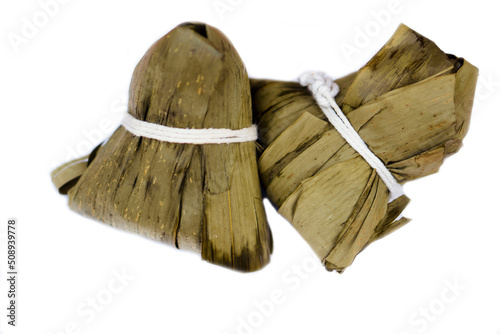 Sticky Rice dumpling or Bajang in Thai language, made from  steamed rice ,grains, pork, salty eggs ,nut, wrapped in dry leaves in pyramid shape isolated on white background. Concept : Chinese dessert. photo