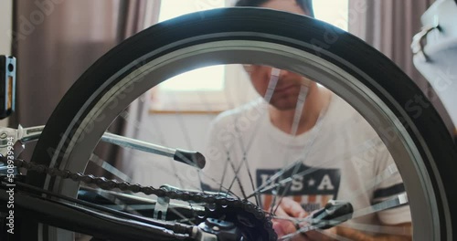 man rotates a bicycle wheel, master repairs a bicycle. Close-up, home master checking the wheel. photo