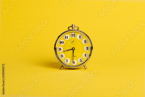 Round yellow alarm clock on a bright yellow background with space for copy