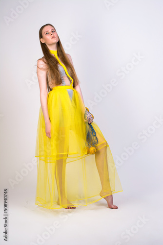 a girl in a yellow dress with a bag of lemons on a white background