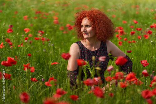 Redhead woman in a poppy field