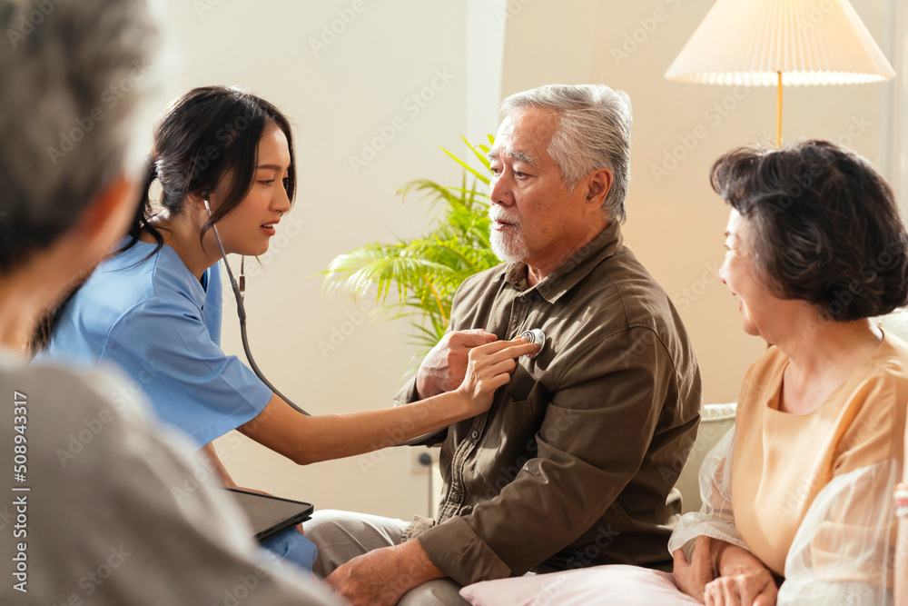 Obraz premium happiness Cheerful elderly woman and men talking with female caregiver nurse doctor having health checking consult at living area,Caretakers with senior couple sitting in living room at nursing home