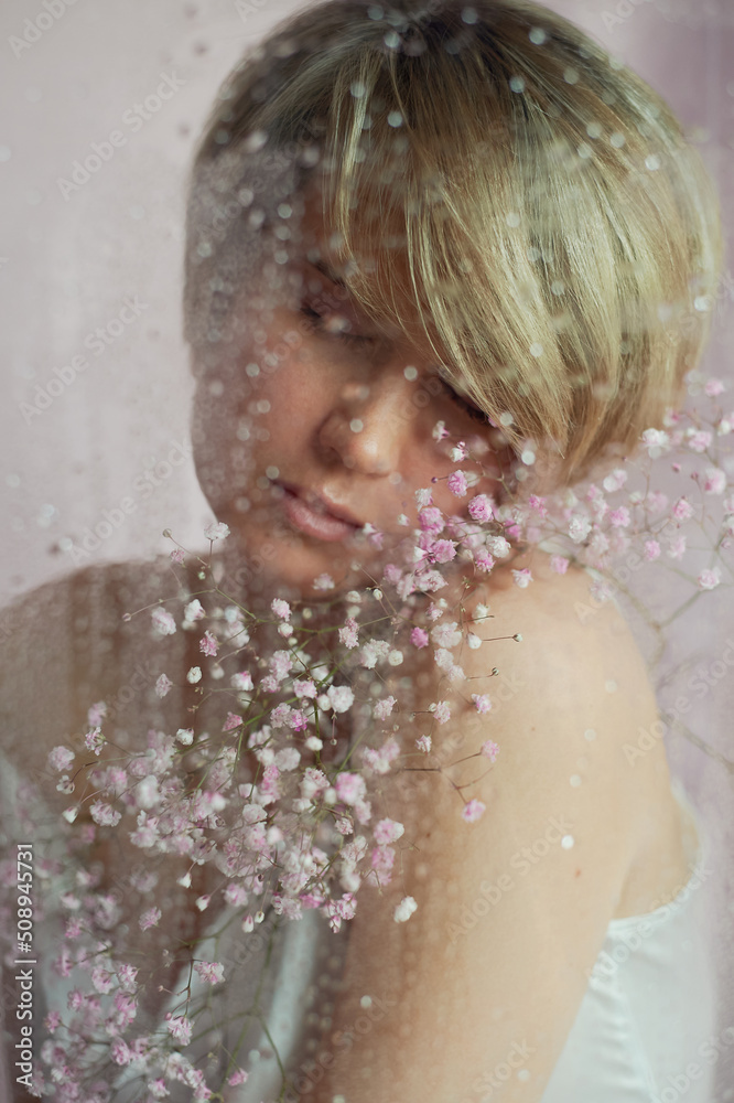 Portrait of a girl on a pink background with flowers. Tenderness and feminine. The sphere of beauty and women's health. Short haircut, blonde hair Portrait of a girl on a pink background with flowers. Tenderness and feminine. The sphere of beauty and women's health. Short haircut, blonde hair