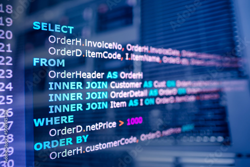 SQL (Structured Query Language) code on computer monitor and server room background. Example of SQL code to query data from a database.