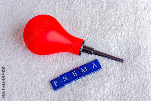 red enema bulb with the word enema on a white blanket photo