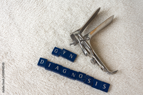 speculum with the words gyn diagnosis on a white blanket photo