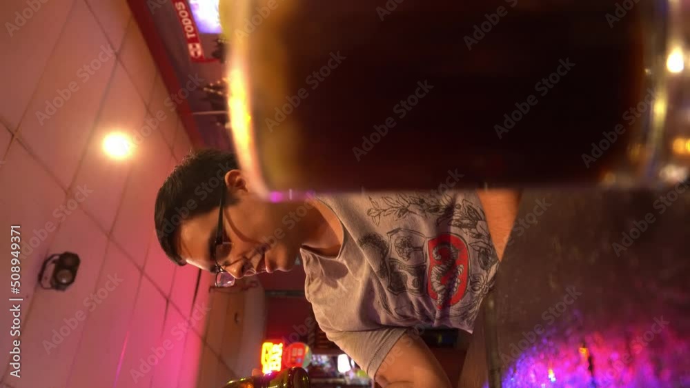 vertical shot of a man drinking beer in a bar a glass of cuba libre defocused foreground