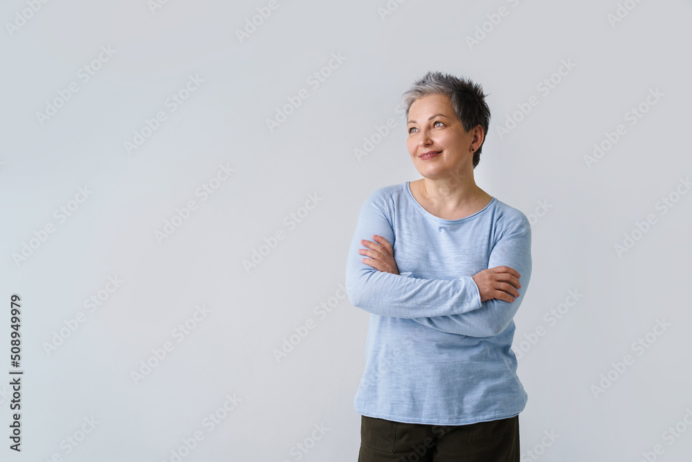 Happy mature grey hair woman posing with hands folded looking sideways up, copy space on left isolated on white background. Healthcare concept. Aged beauty concept Happy mature grey hair woman posing with hands folded looking sideways up, copy space on left isolated on white background. Healthcare concept. Aged beauty concept