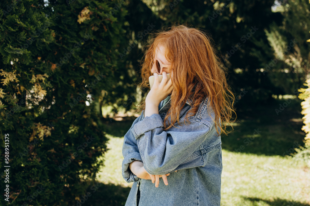 Red-haired girl in a denim jacket talking on the phone Red-haired girl in a denim jacket talking on the phone