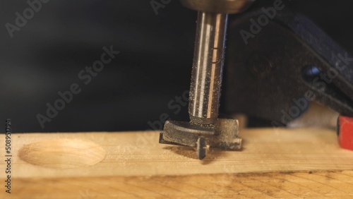 Metal drill for wood. Hole drilling. Work in the workshop. Wooden block. Close-up. The work of a carpenter. Product manufacturing. Natural material.