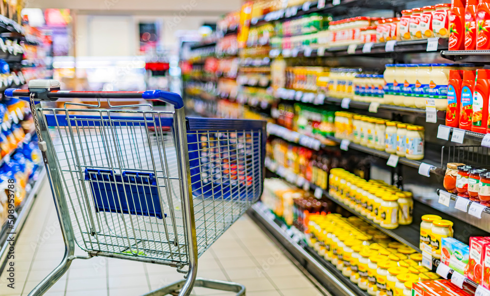 A shopping cart by a store shelf in a supermarket