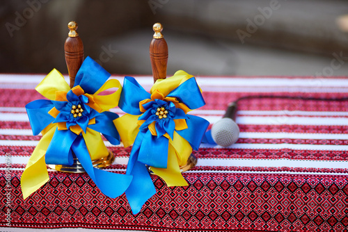 Vintage school bell as a symbol of the beginning and end of the school year in Ukraine. The bell is tied with a yellow-blue ribbon in the color of the flag of Ukraine. There is a microphone nearby.