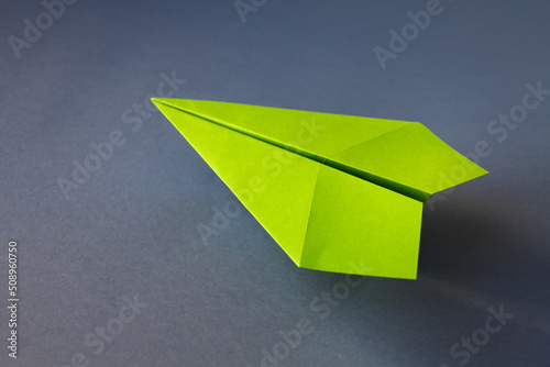 Green paper plane origami isolated on a grey background