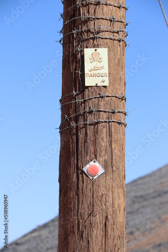 A wooden pole with a danger sign, reflector and barb wire. Djabal Achdar mountains. photo