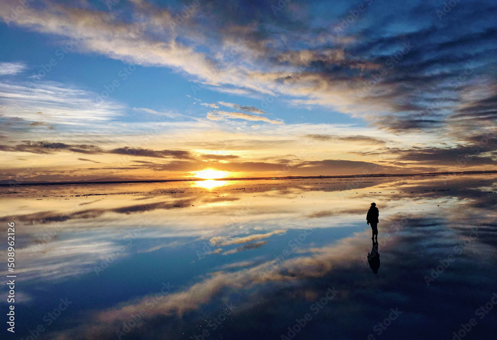 A person looking at the reflective sunrise at Uyuni Salt Flat, Bolivia