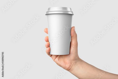 Paper coffee cup with plastic cap in a hand mockup template, isolated on light grey background. High resolution.