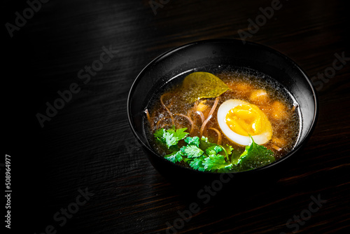 Japanese ramen soup with tofu and egg on black wooden table background