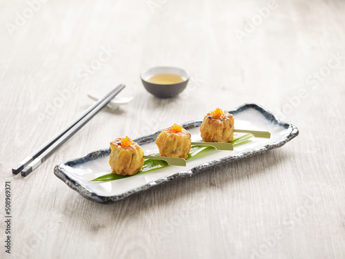 Pan-fried Siew Mai with Foie Gras Sauce served in a dish isolated on mat side view on grey background