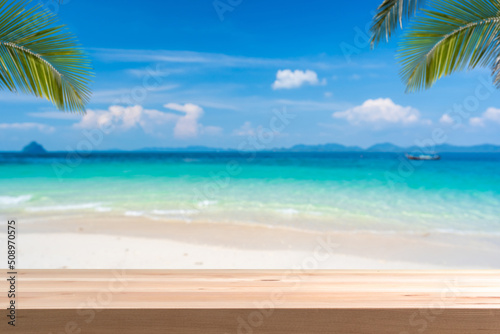 Fototapeta Naklejka Na Ścianę i Meble -  Wooden table top with tropical beautiful white sand beach and blue sky background, Summer vacation concept and copy space