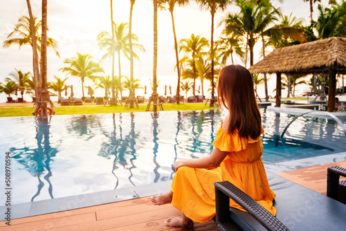 Quadro su tela Young female relaxing and looking beautiful sunset over the sea at a tranquil tr