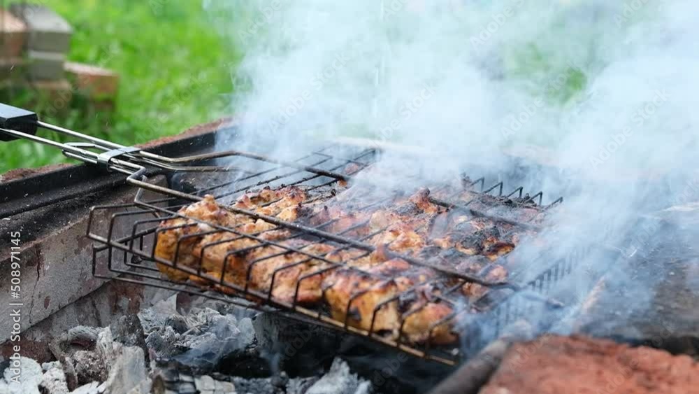 Cooking kebabs on grid. Grilling meat on hot coals. Slow motion of drops of water or sauce and clouds of smoke. Selective focus. Cooking kebabs on grid. Grilling meat on hot coals. Slow motion of drops of water or sauce and clouds of smoke. Selective focus.