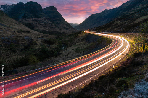 Car light trails on winding road through the highlands near Glencoe in Scotland at dusk