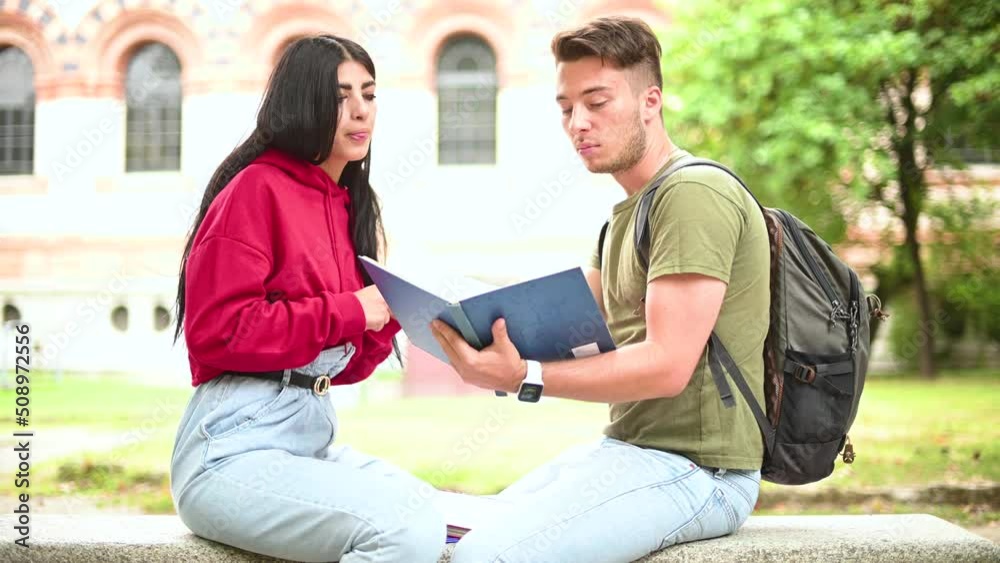 Two students studying together sitting on a bench outdoor Two students studying together sitting on a bench outdoor